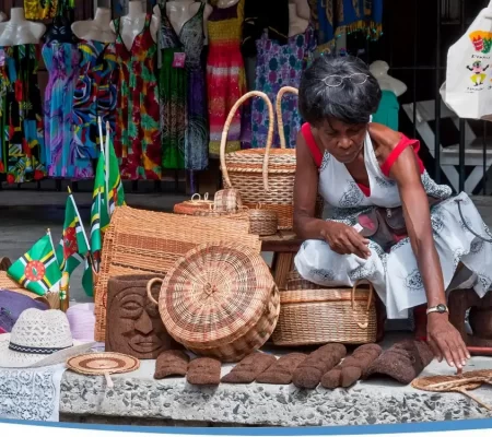 A woman sits on the ground surrounded by baskets and various items, engaged in her surroundings.